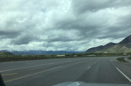 Road curving out of sight with mountains in the background.