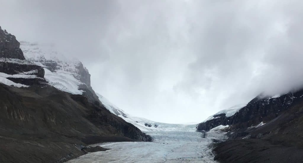 Large glacier between craggy mountains enveloped in mist. Such a dramatic description!